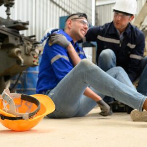 worker in pain sitting on ground holds their shoulder