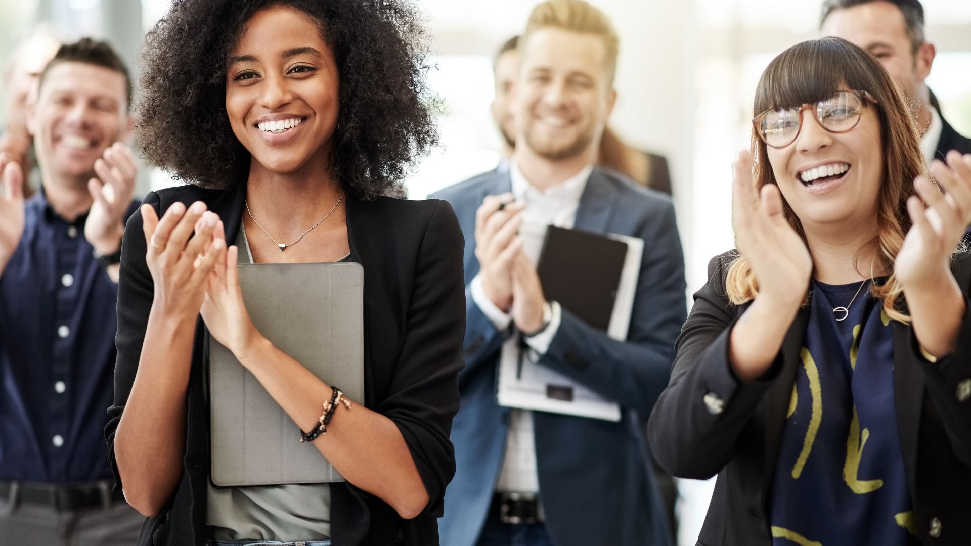 employees holding tablets clapping and smiling
