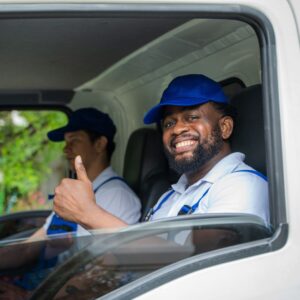 A man driving a work truck, smiling and giving a thumbs up